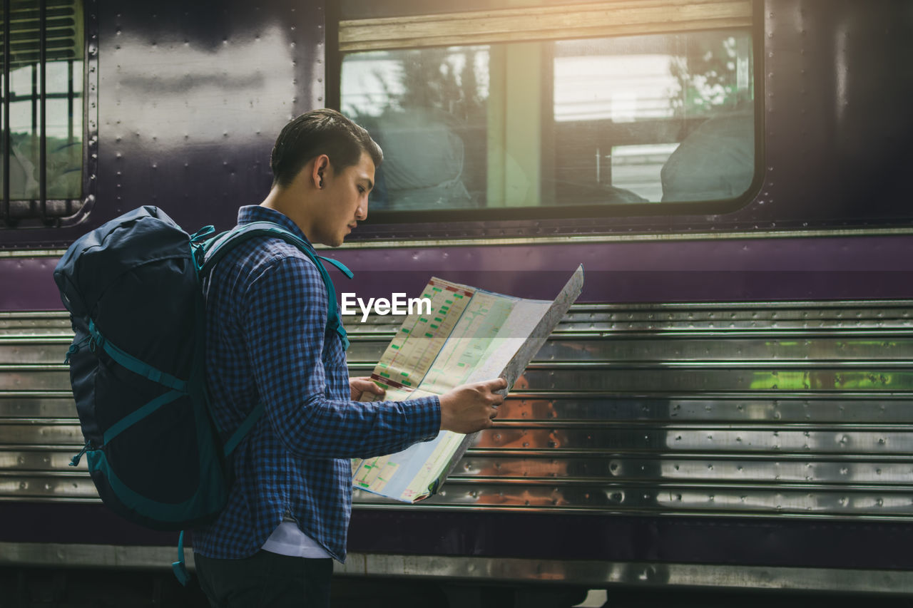 Man reading map while standing at railroad station platform