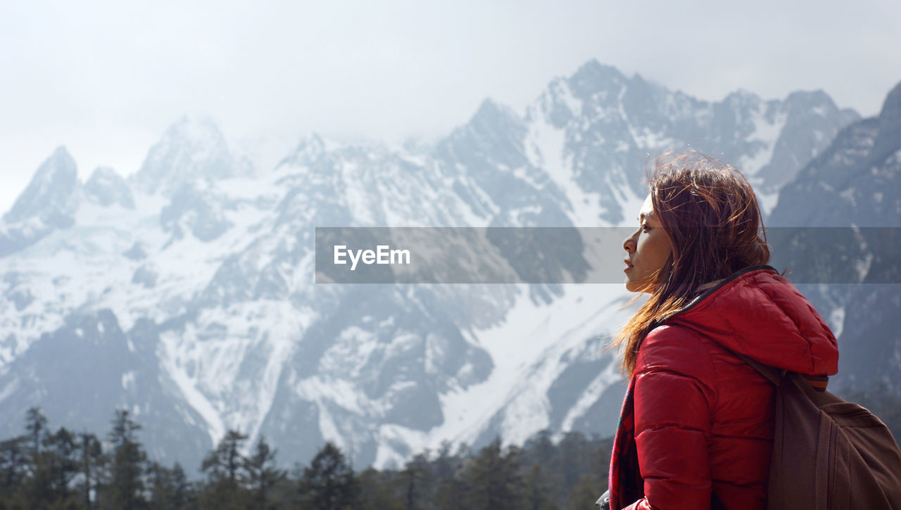 Side view of woman looking away against snowcapped mountains
