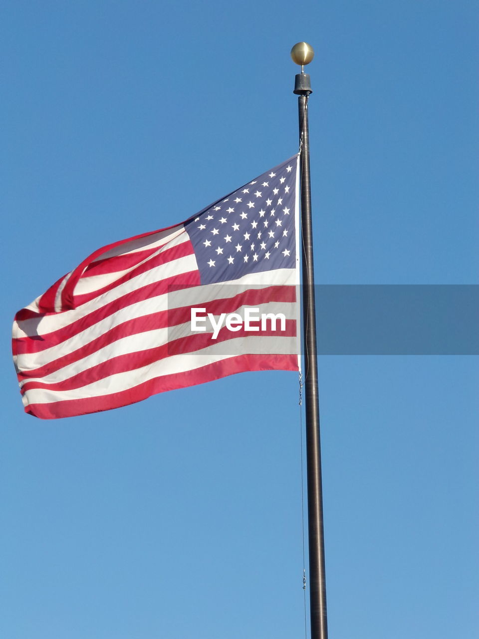 Low angle view of american flag against clear blue sky