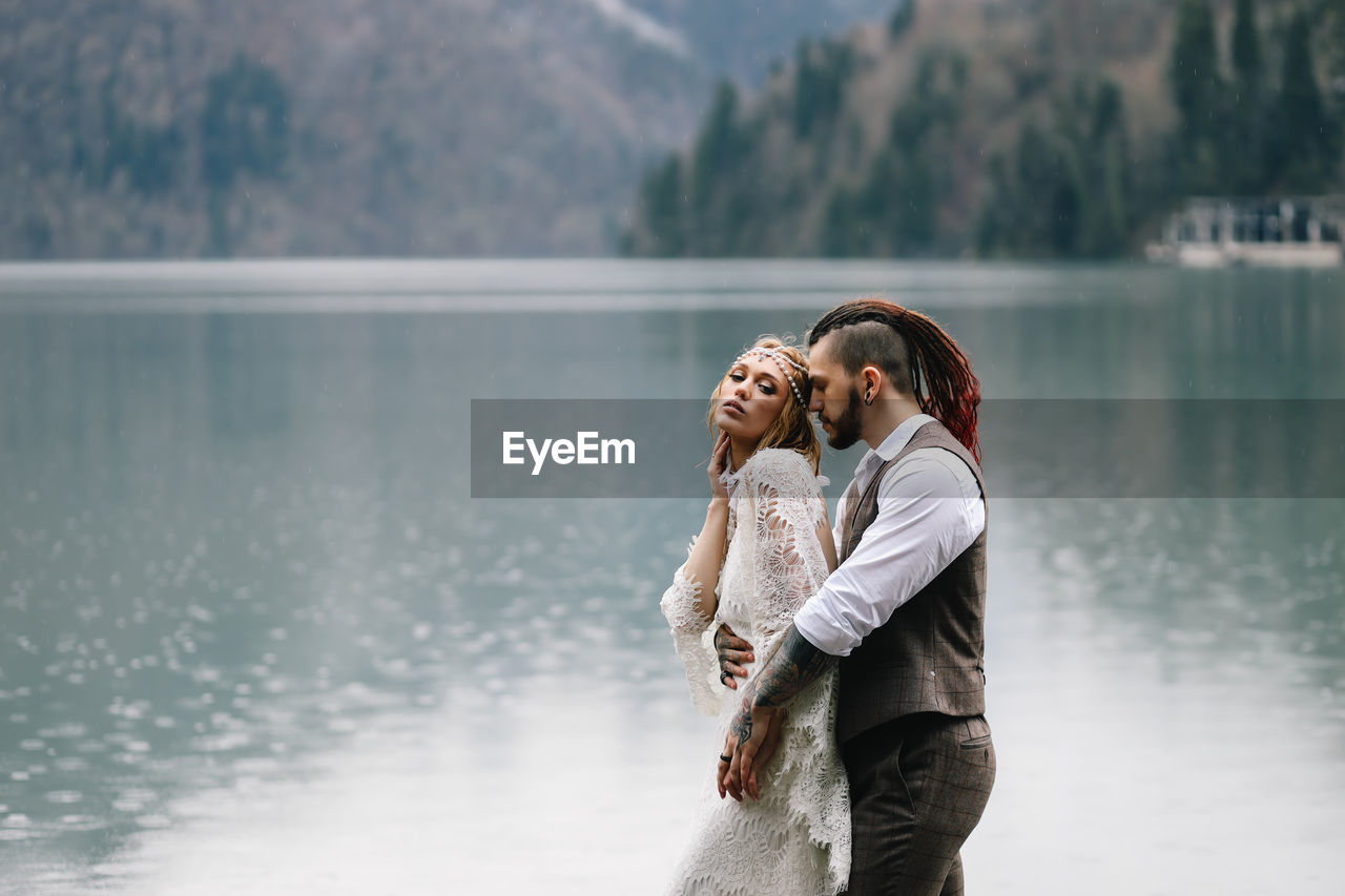 A happy couple in love and married embrace in nature by the lake and the misty mountains