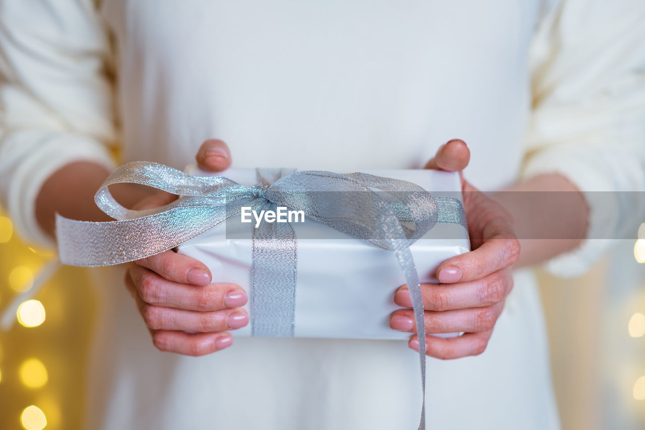 Female hands hold christmas or new year gift box on boke background. christmas