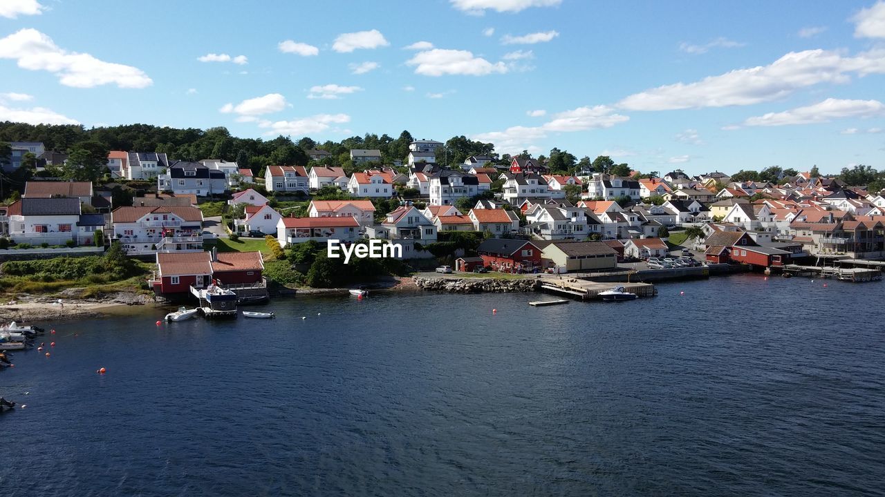 High angle view of buildings by lake against sky