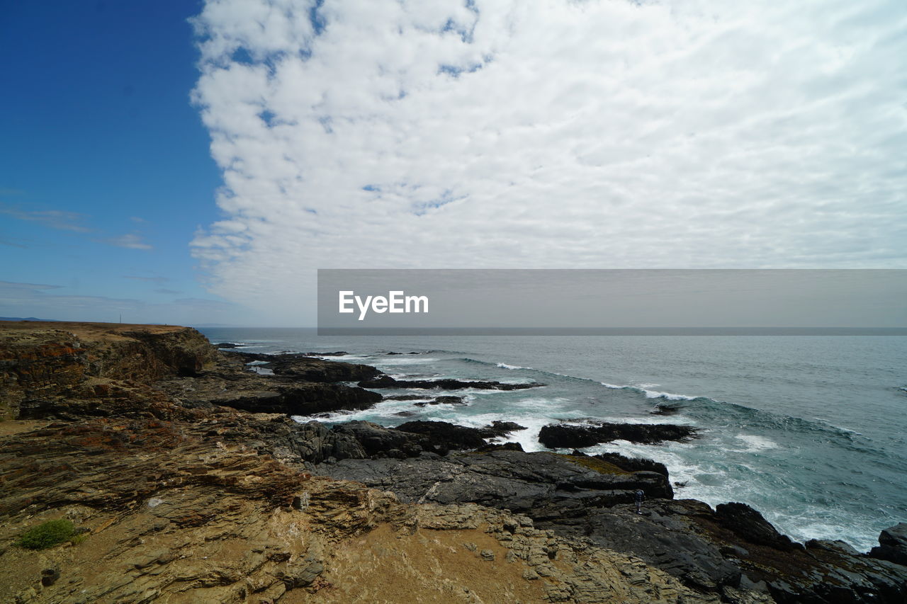 SCENIC VIEW OF ROCKY BEACH AGAINST SKY