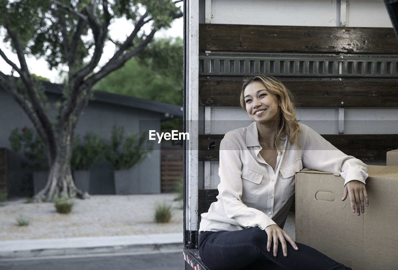 Woman sitting inside moving truck with boxes