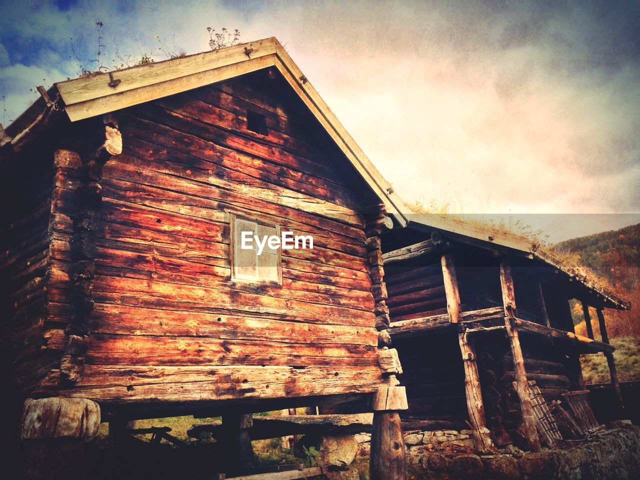 Low angle view of old wooden house against cloudy sky