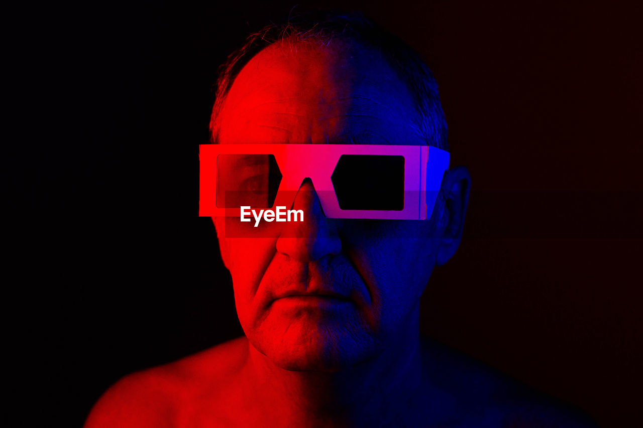 Close-up portrait of man against black background with 3-d glasses 
