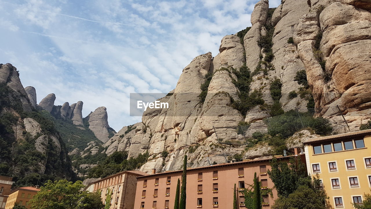 LOW ANGLE VIEW OF BUILDINGS AND MOUNTAIN AGAINST CLOUDY SKY