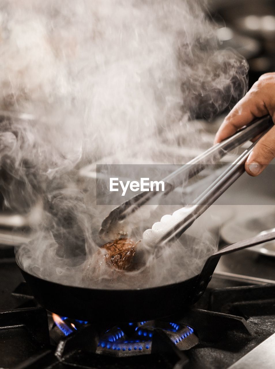 Chef preparing steak in kitchen.