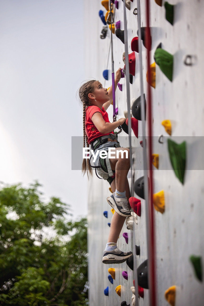 Confident child climbs wall with rope and harness. joy, courage, and coordination in action.