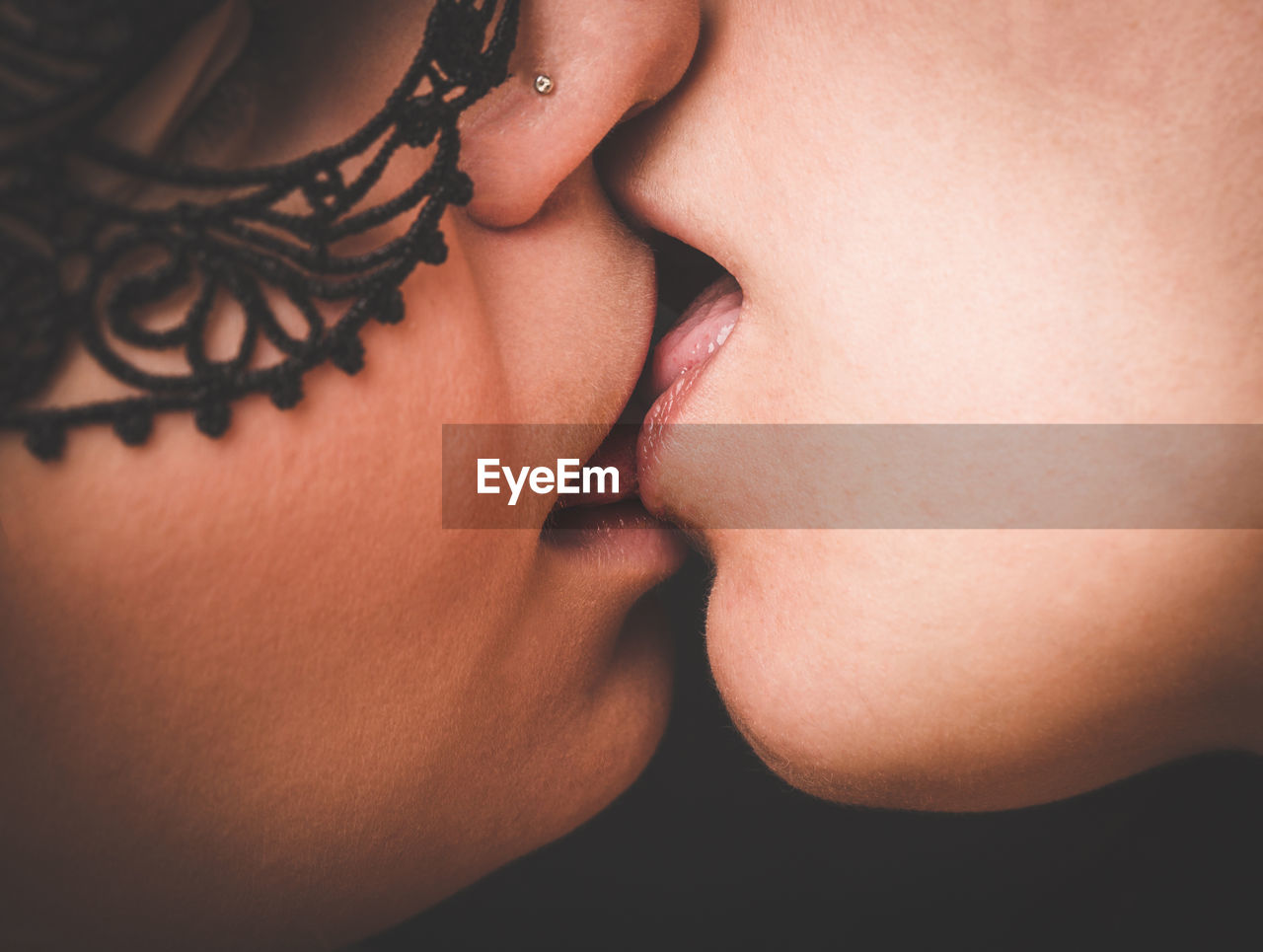 Close-up of lesbian couple kissing against black background