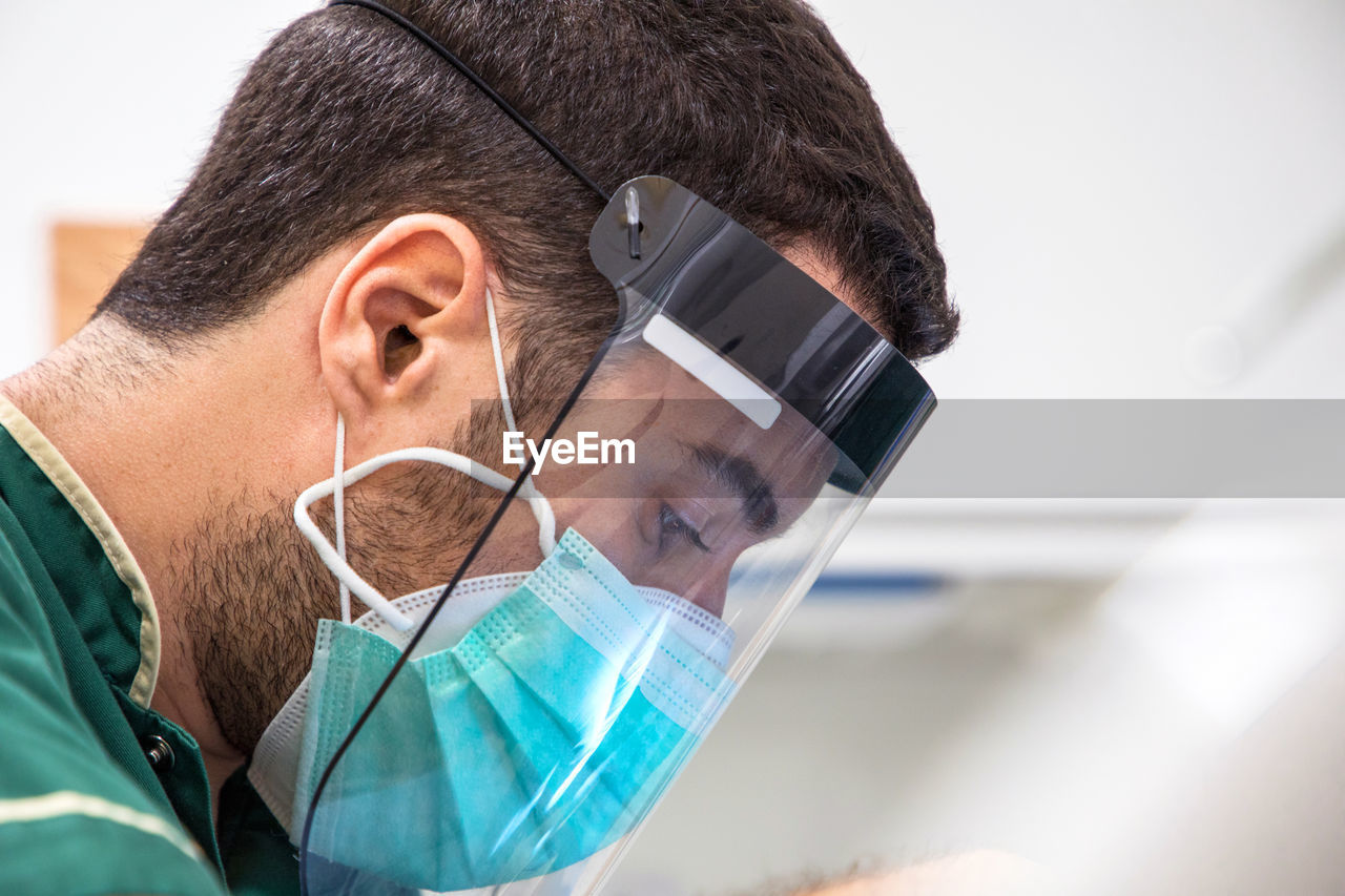 Side view of male doctor with face mask and face shield while working