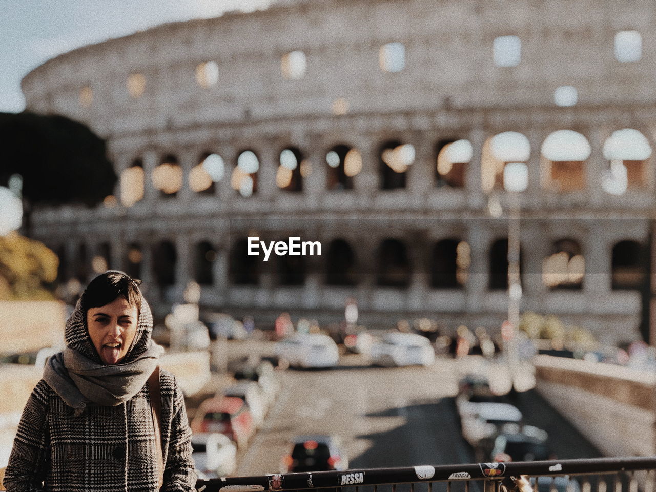 Portrait of woman sticking out tongue
 against coliseum