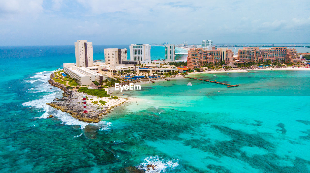 Aerial view of buildings by sea against sky