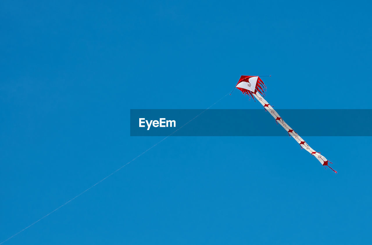 Low angle view of flag flying against clear blue sky