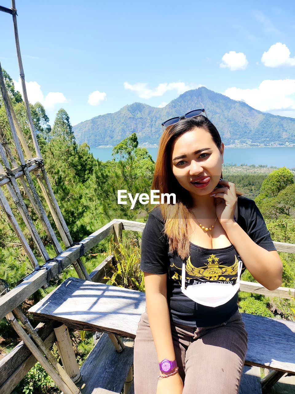 PORTRAIT OF WOMAN SITTING AGAINST MOUNTAIN