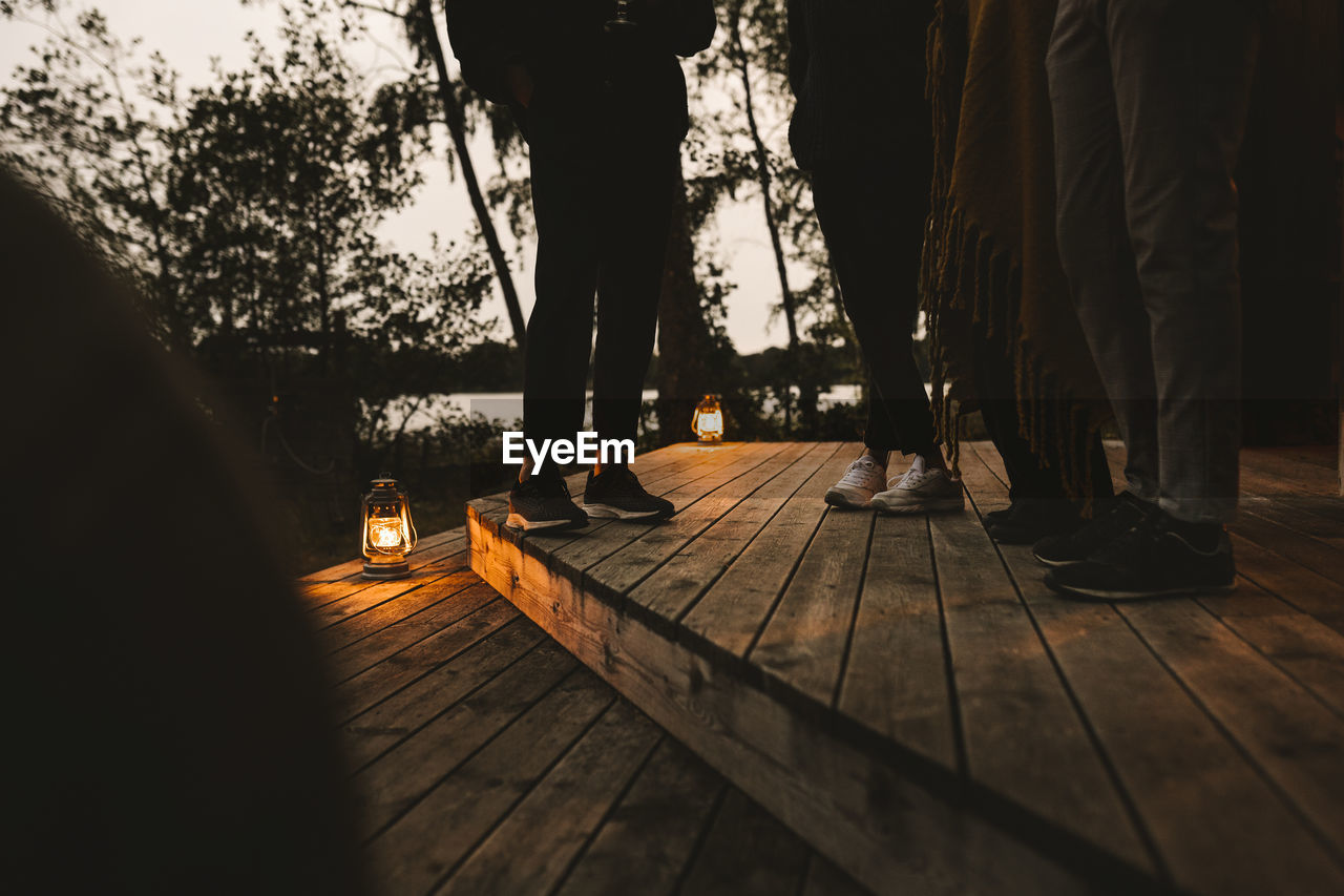 Low section of male and female friends standing over wooden steps during social gathering