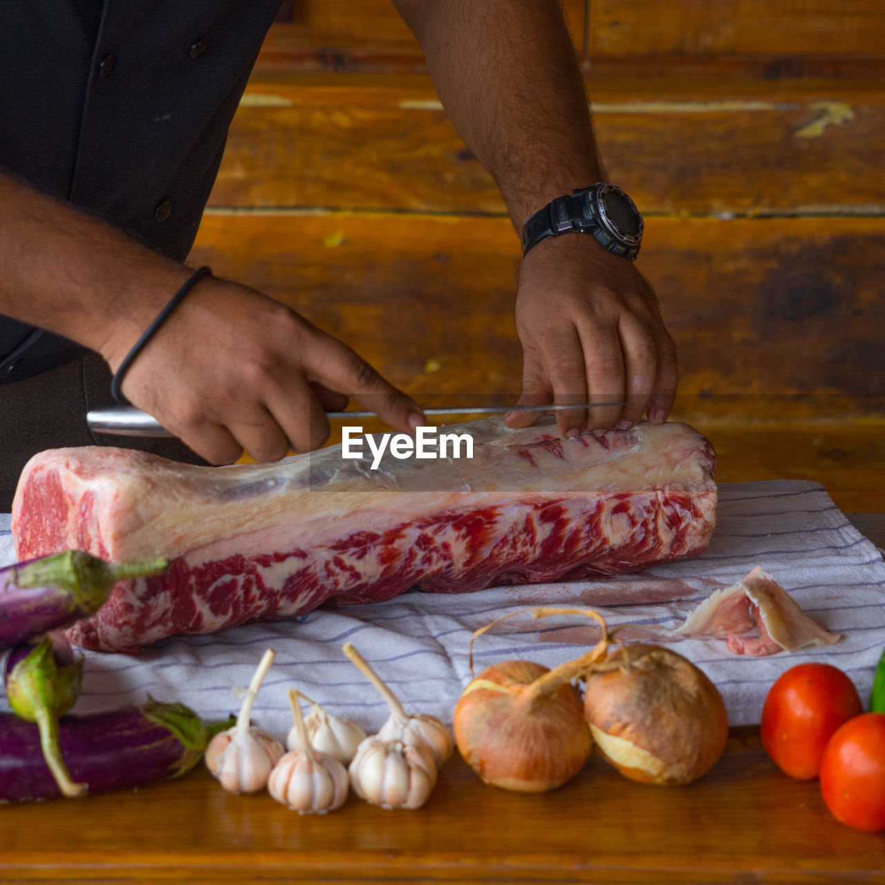 Midsection of chef cutting beef on table