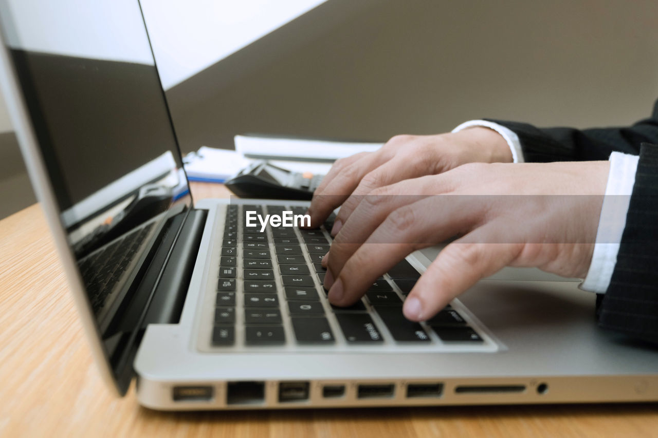CLOSE-UP OF PERSON USING LAPTOP