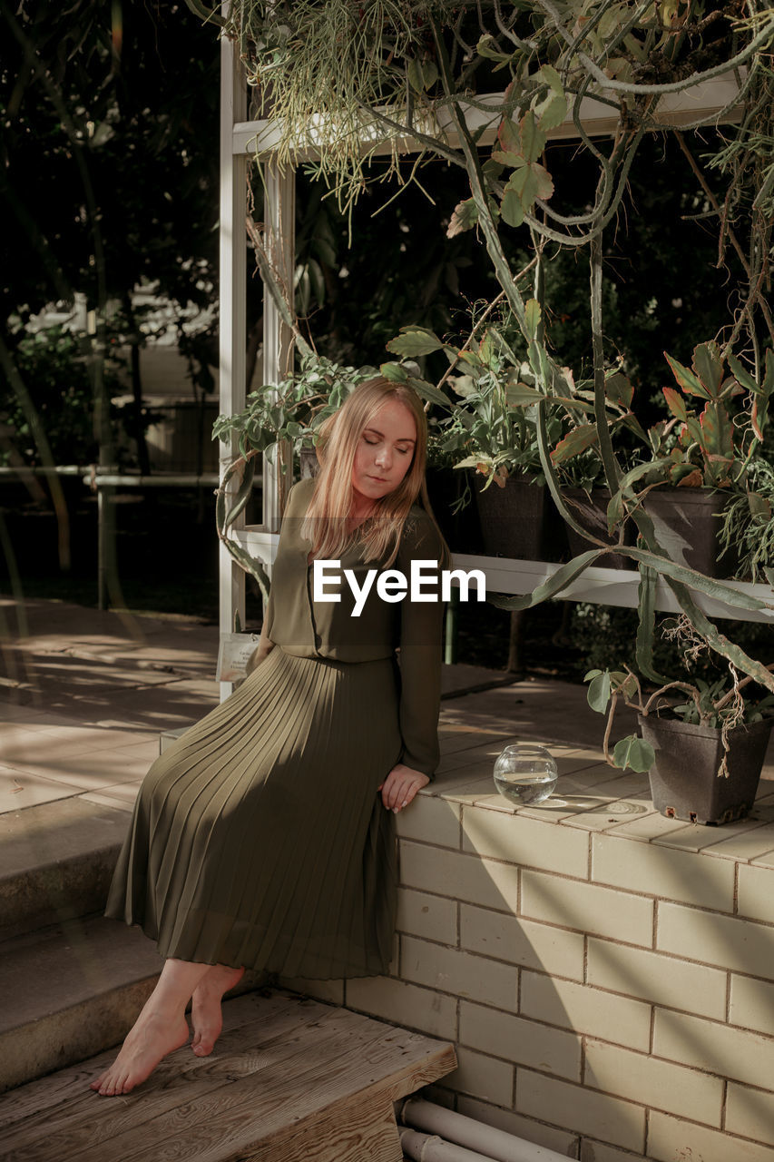 Woman sitting on staircase by plants