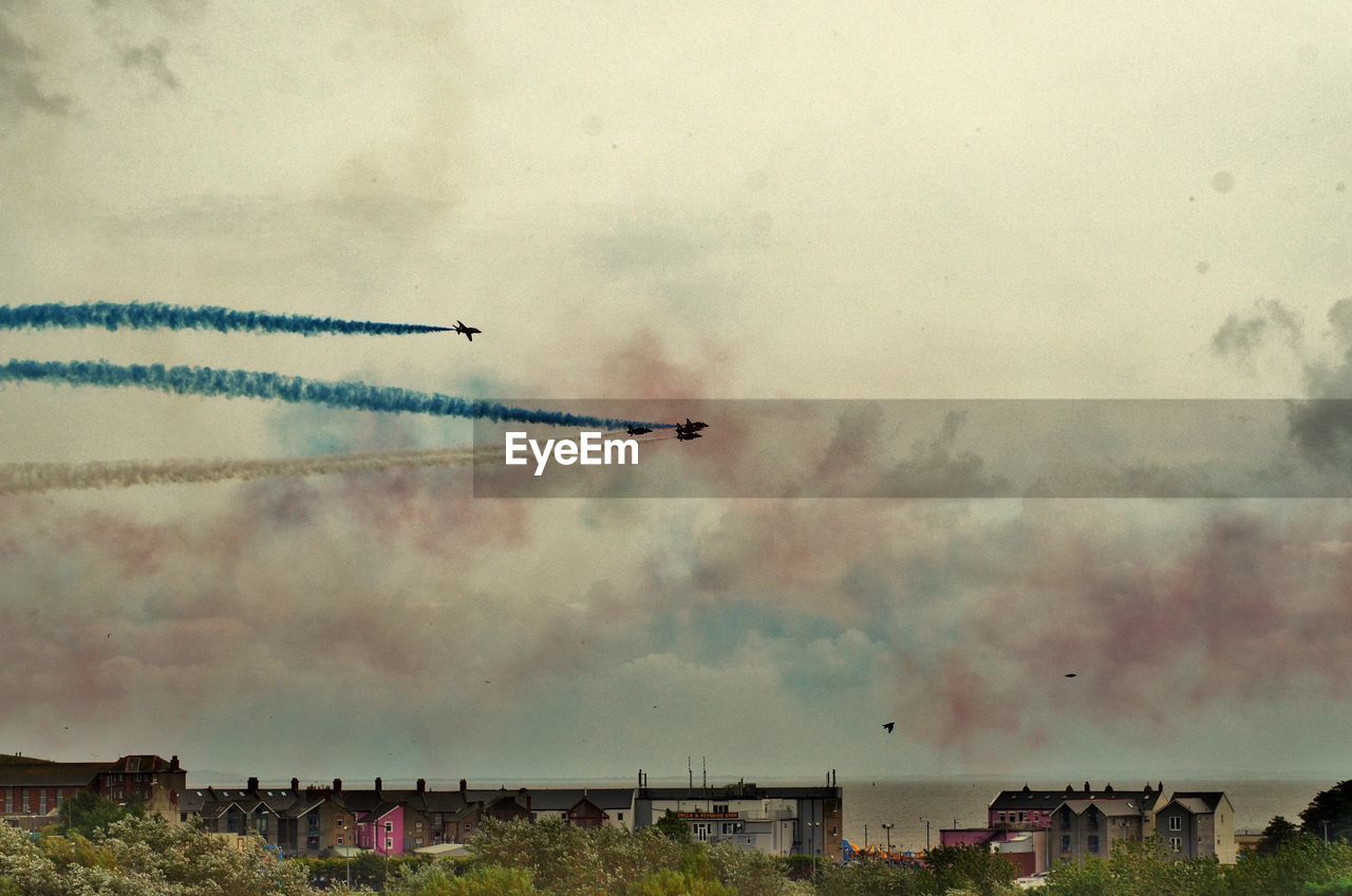 Low angle view of airplanes with vapor trail in sky during airshow