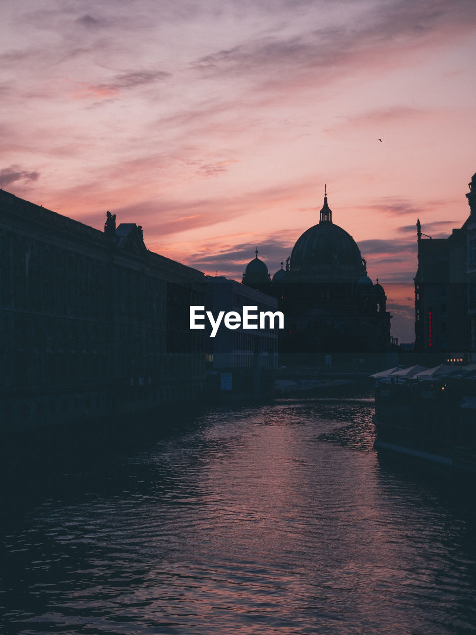 River amidst buildings against sky during sunset