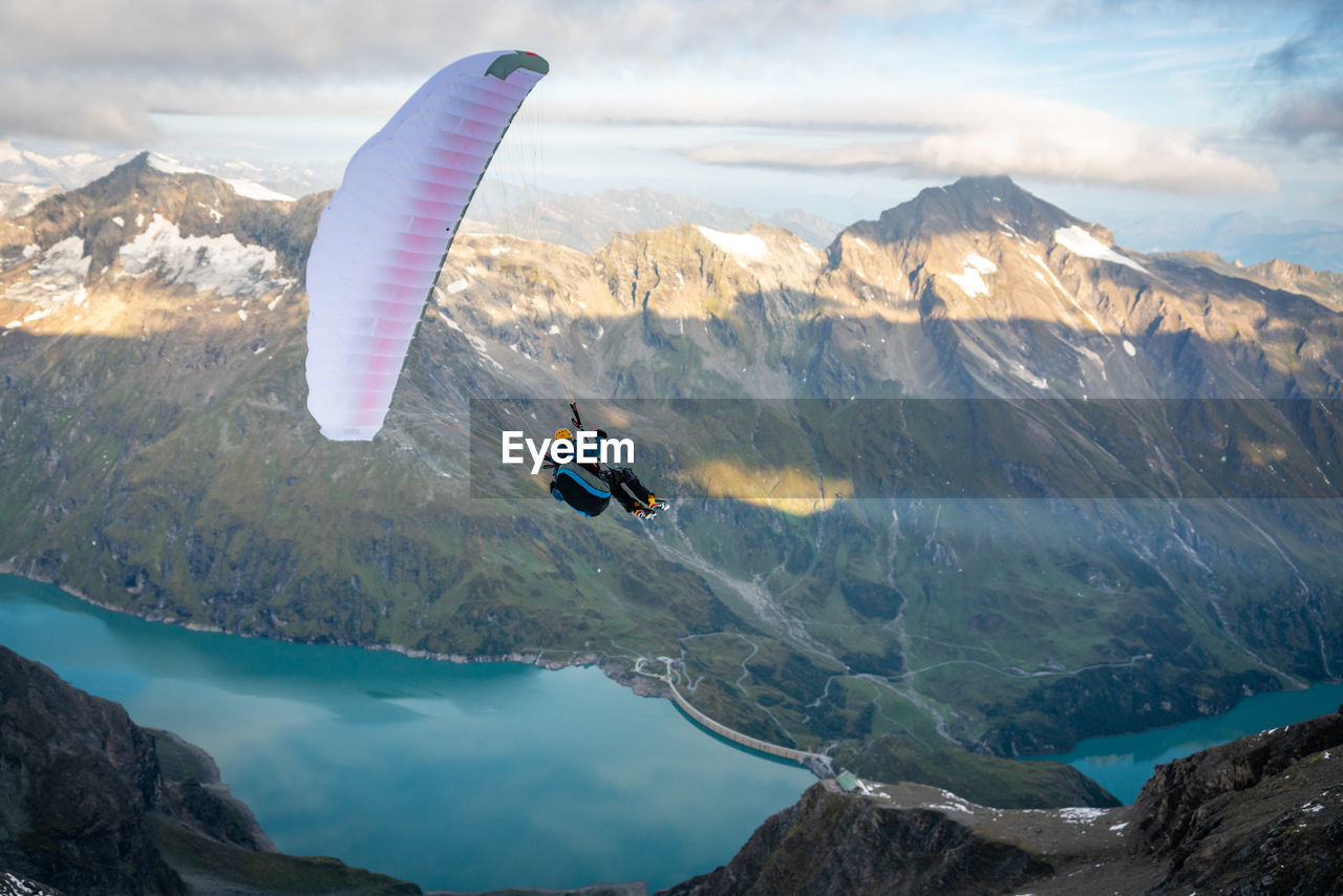 Man paragliding over mountains against sky