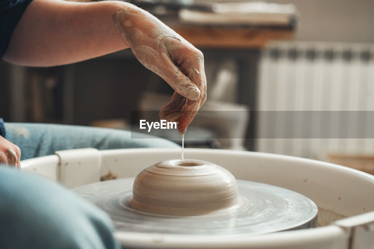 The hands of ceramist create pottery on a pottery wheel