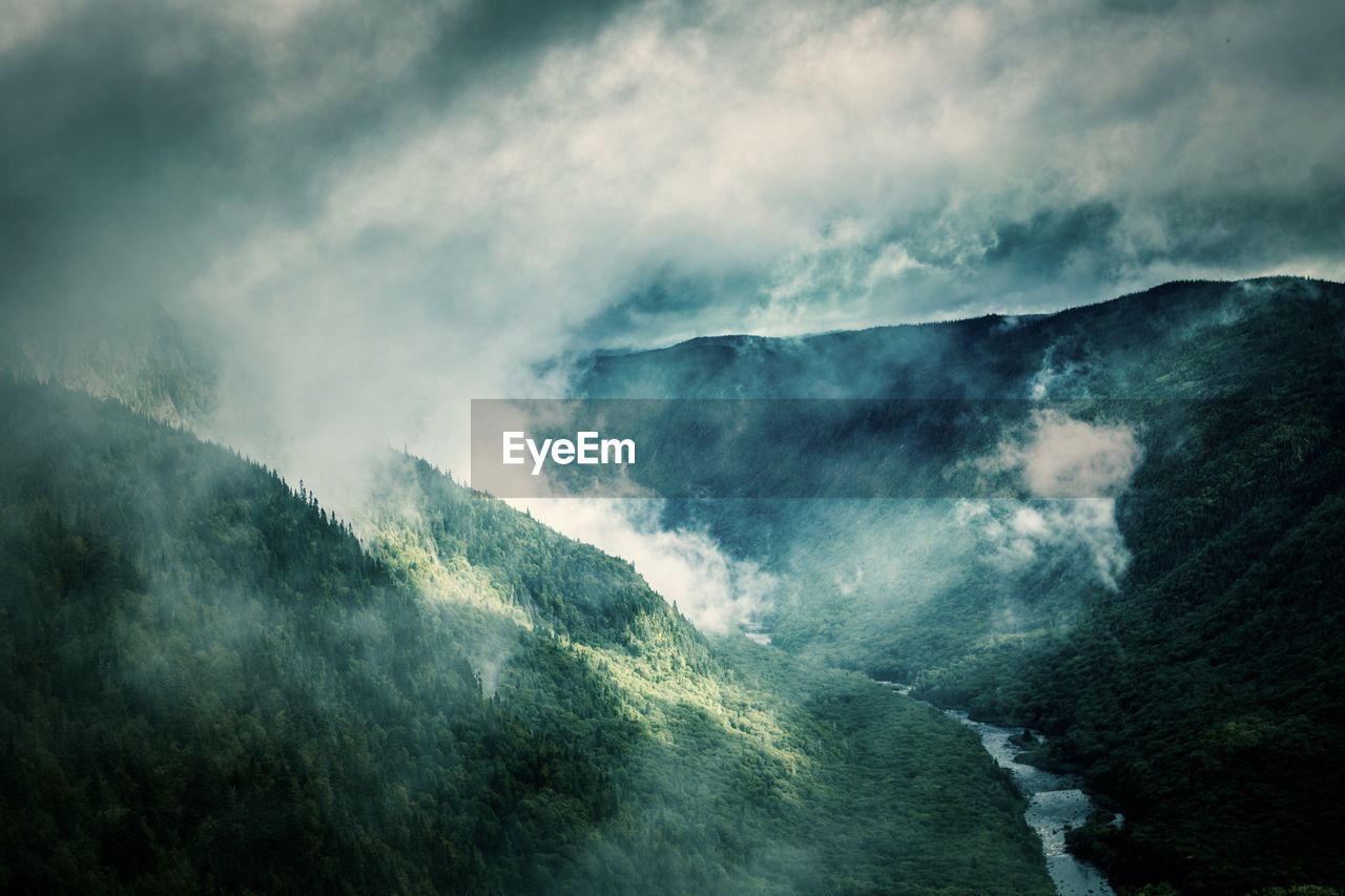 SCENIC VIEW OF WATERFALL AGAINST MOUNTAINS