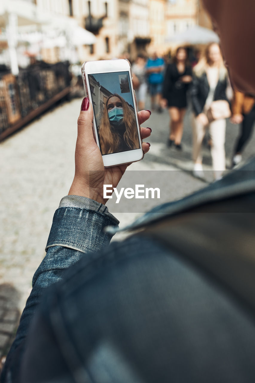 Young woman having video call talking while walking downtown in the evening wearing the face mask