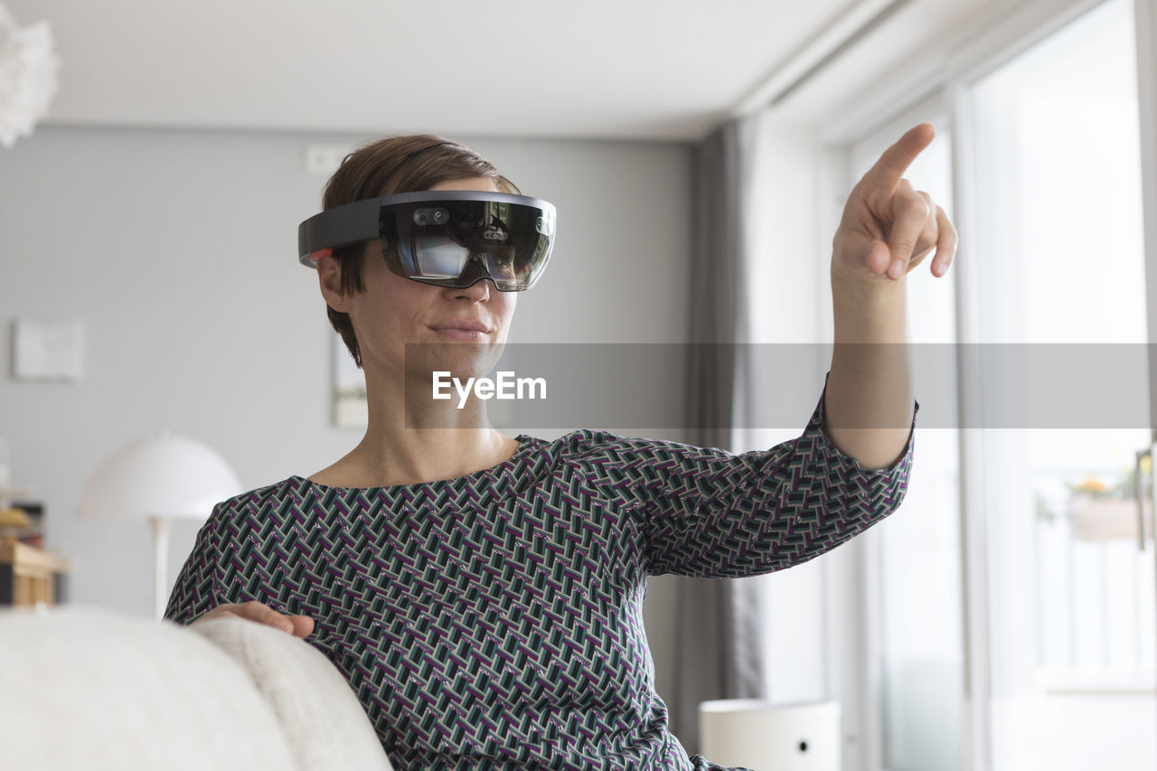 Woman at home using augmented reality glasses at home
