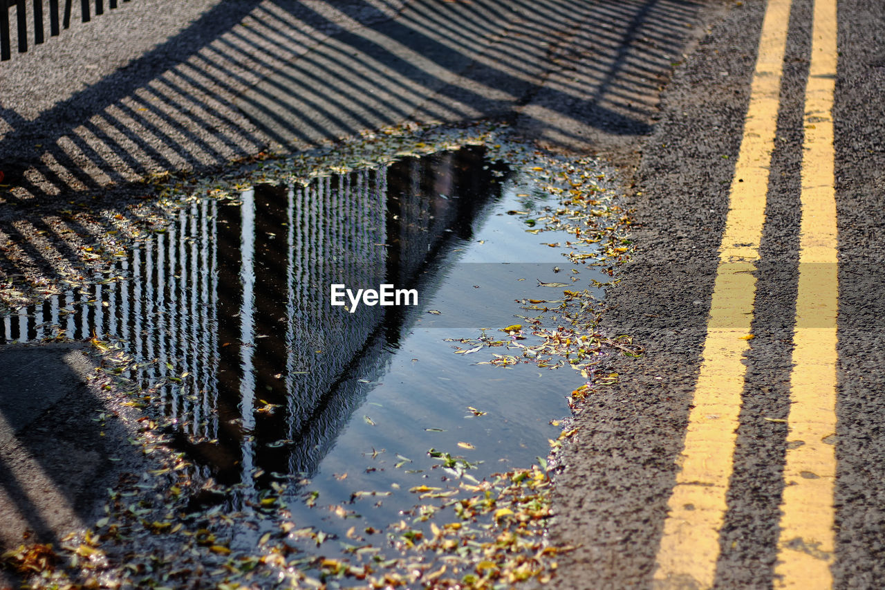 Reflection of railing in puddle on road