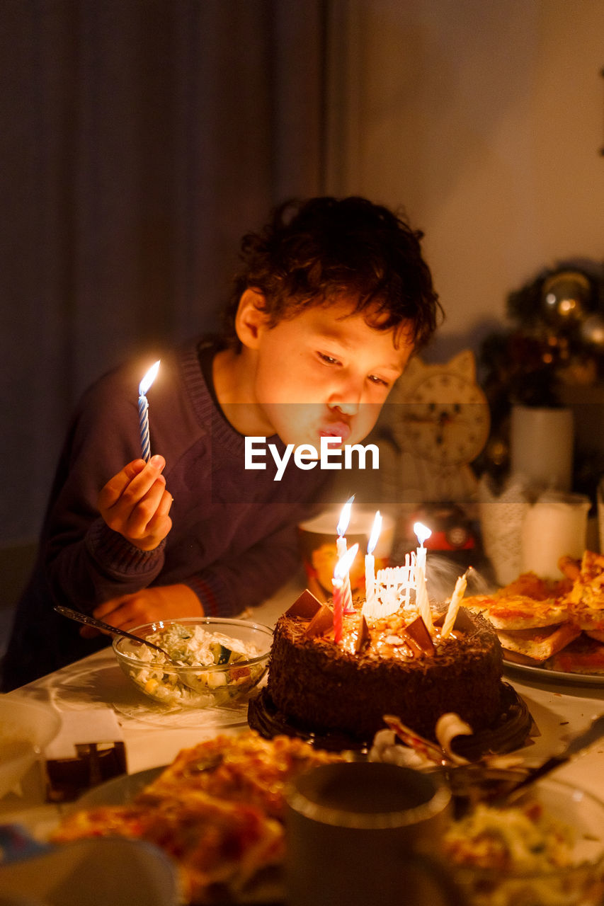 Cute curly boy with candles on birthday cake where is the candle in his hand