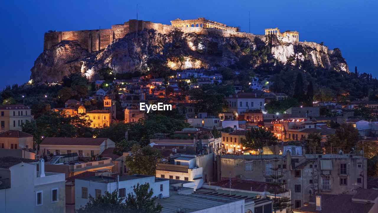 Buildings against acropolis of athens at night