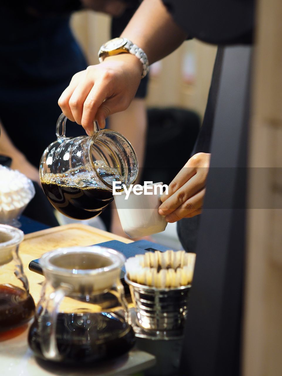 Cropped hand of woman pouring black coffee in cup