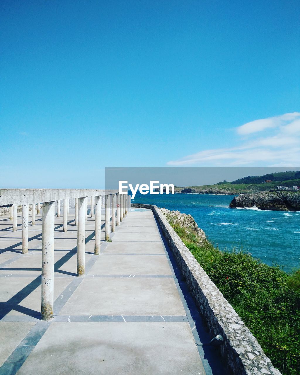 Pier over sea against clear blue sky