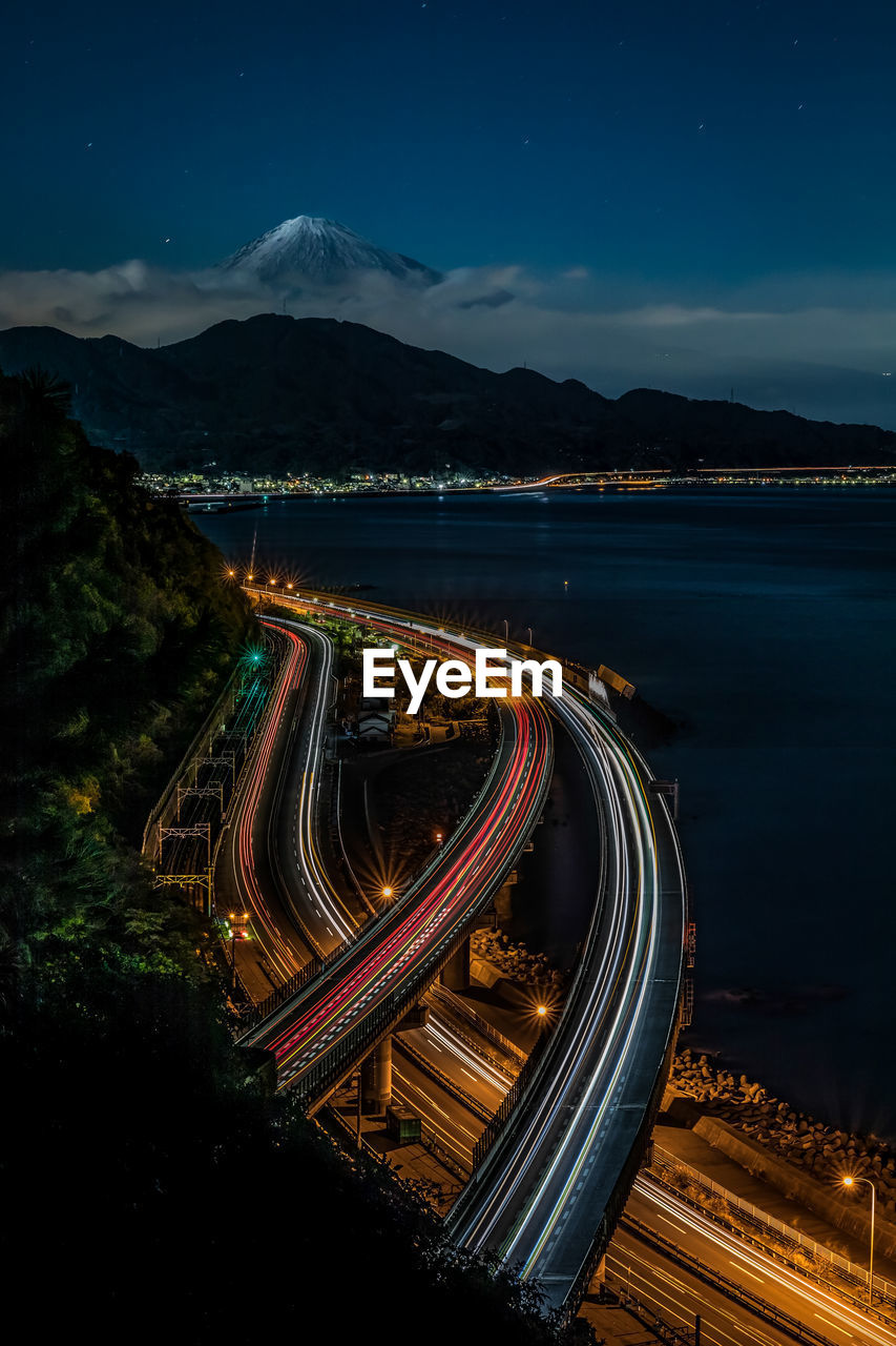 Aerial view of light trails on road against sky at night