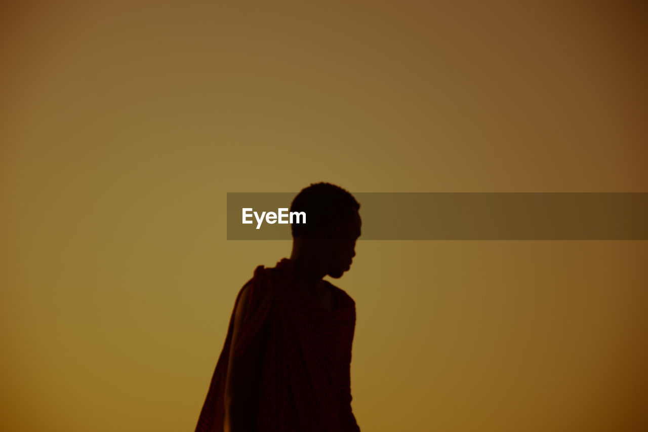 Man standing against orange sky during sunset