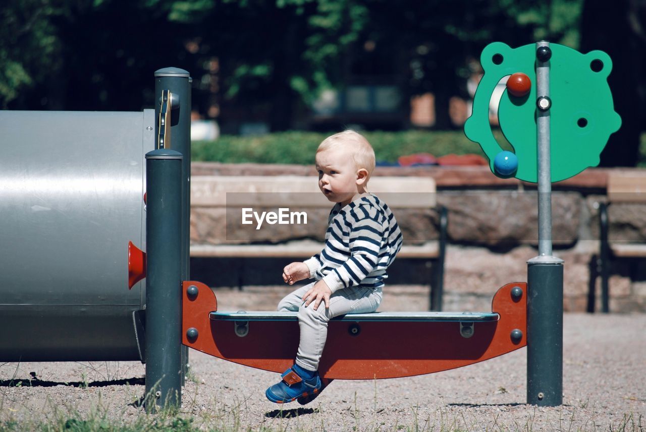 Boy sitting on outdoor play equipment at playground