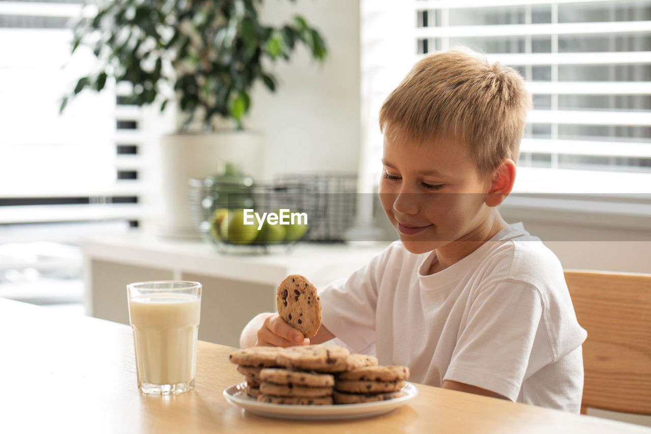 portrait of boy eating food on table at home