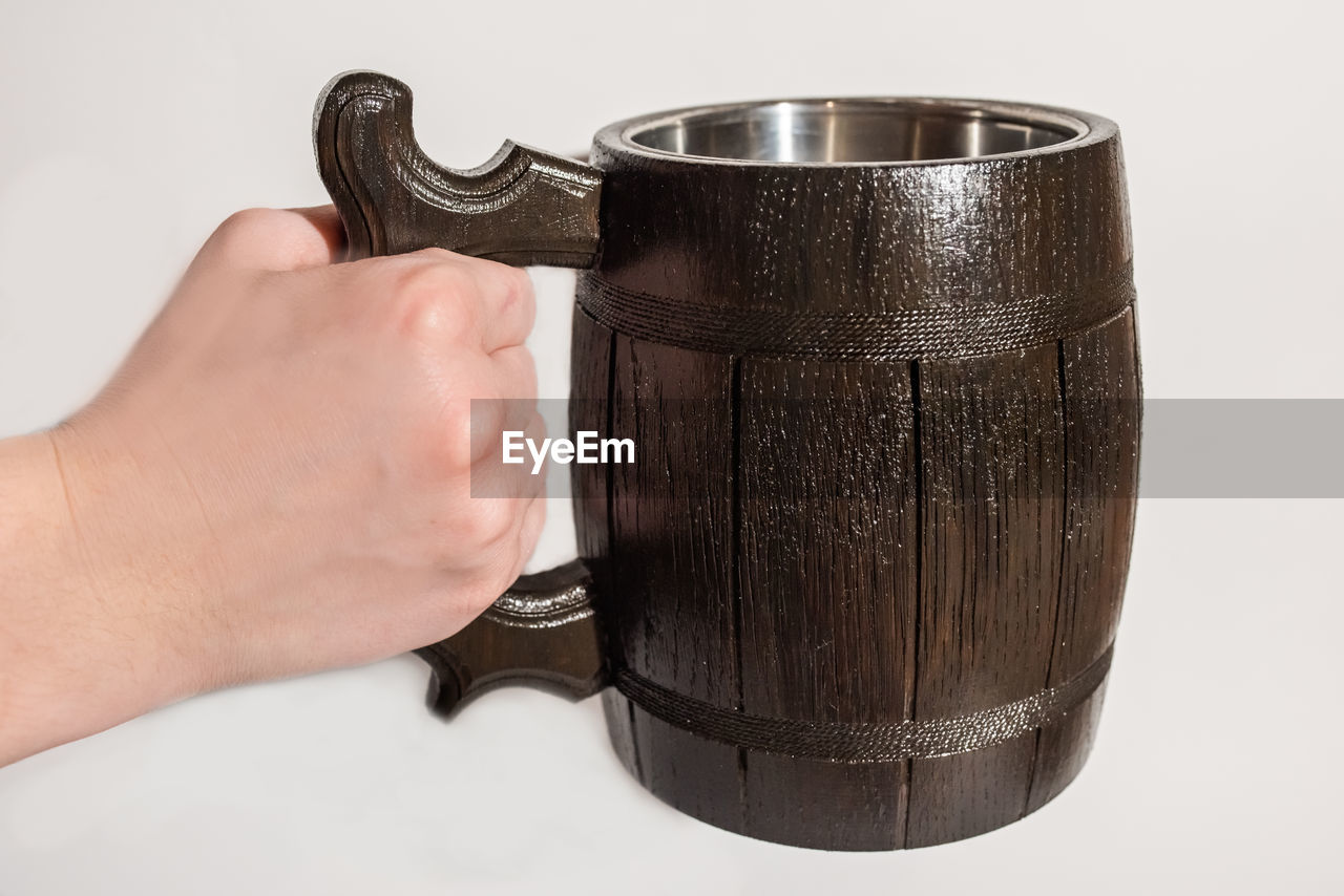 Close-up of hand holding container over white background