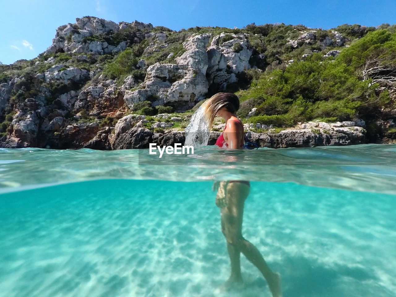 Side view of young woman swimming in sea against mountain