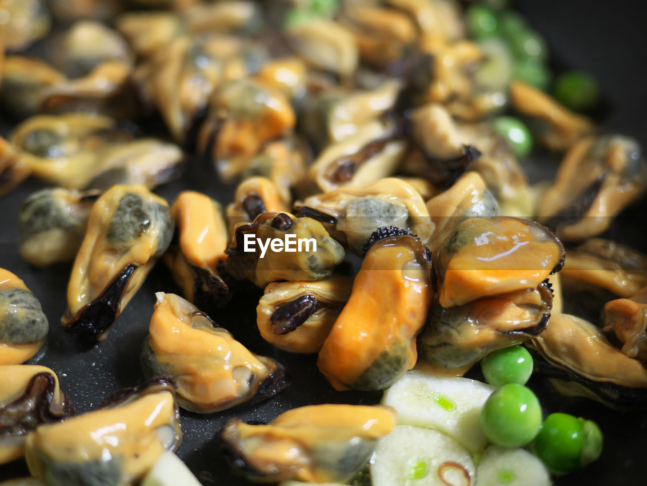 Close-up of mussels and green peas in frying pan