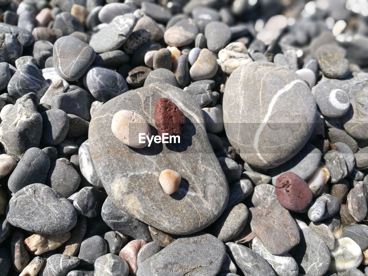 FULL FRAME SHOT OF PEBBLES ON ROCKS