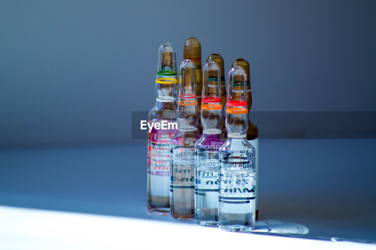 studio shot, container, indoors, no people, distilled beverage, drink, bottle, alcoholic beverage, blue, colored background