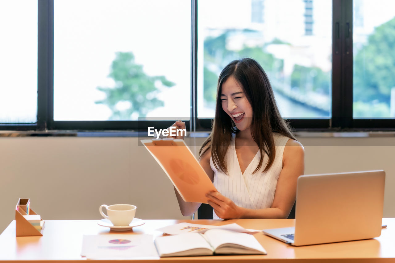 young woman using laptop while sitting on table