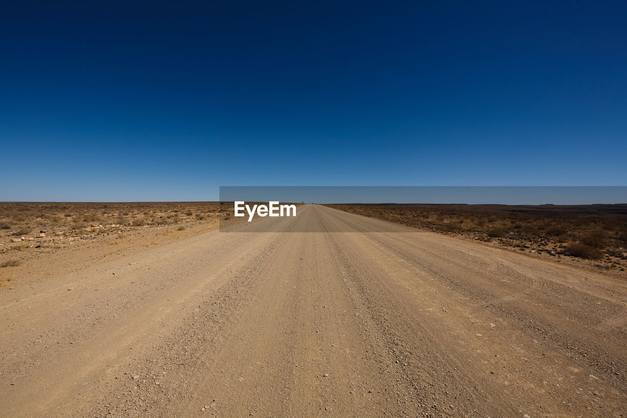 Scenic view of desert against clear blue sky