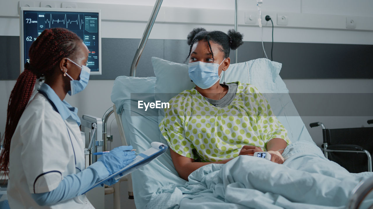 Doctor discussing with patient in ward at hospital