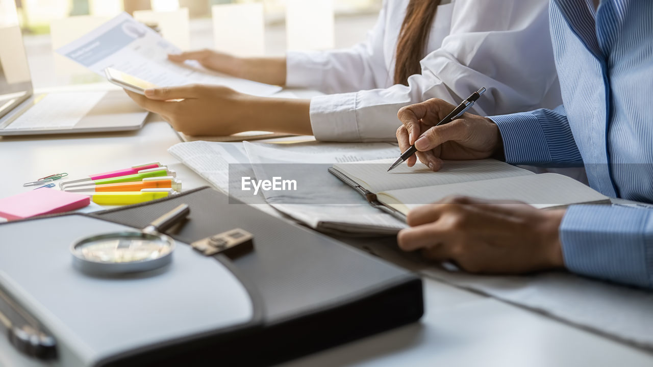 Midsection of man holding paper at table