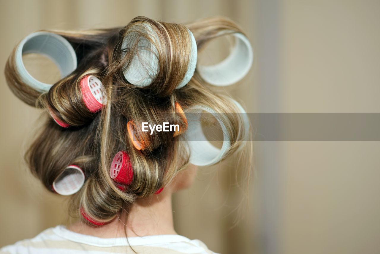 Rear view of woman with hair curlers at salon