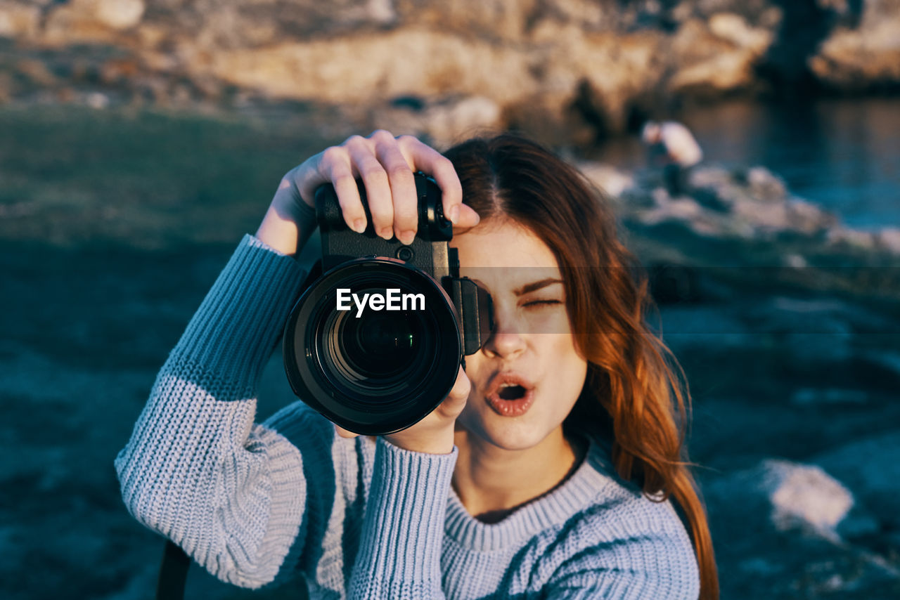 PORTRAIT OF YOUNG WOMAN HOLDING CAMERA